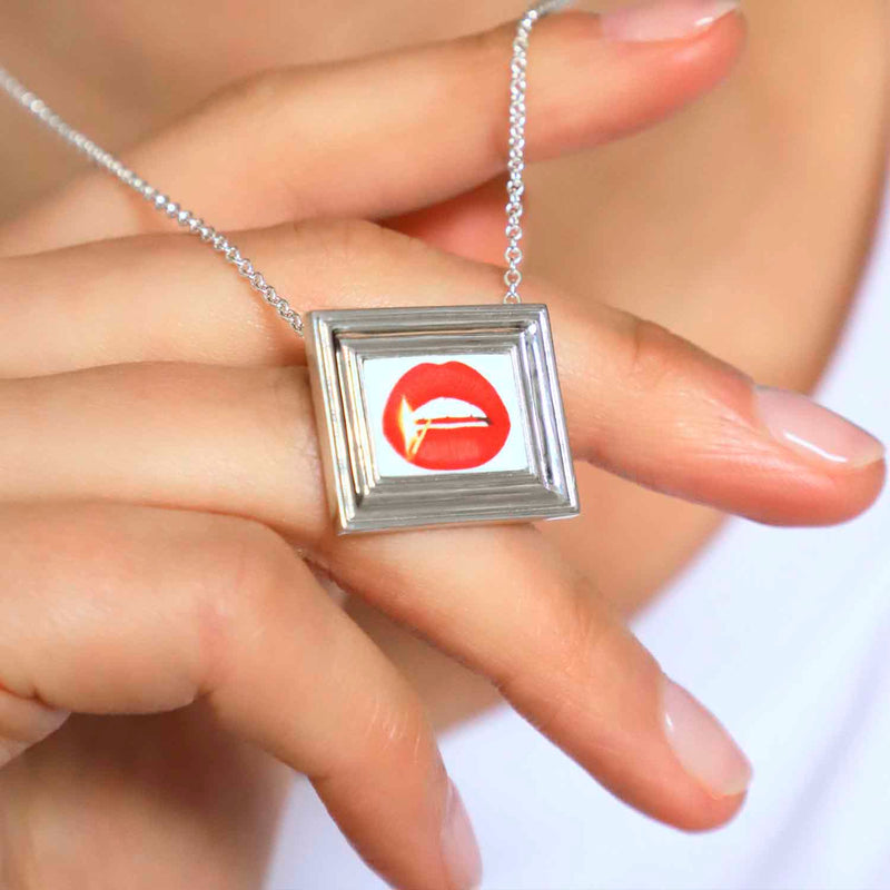 Framed Match And Lips Necklace by Gina Potter And Jennifer House worn on a models hand